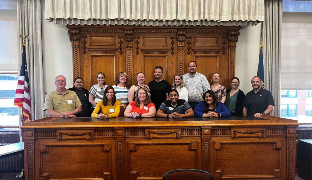 group of people sitting at a large wood desk